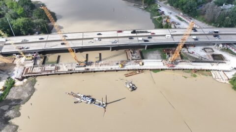 A birds-eye view of temporary trestle bridge and heavy equipment constructing new westbound lanes of I-10 across City Park Lake in Baton Rouge.