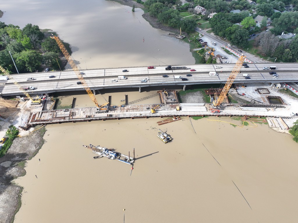 A birds-eye view of temporary trestle bridge and heavy equipment constructing new westbound lanes of I-10 across City Park Lake in Baton Rouge.