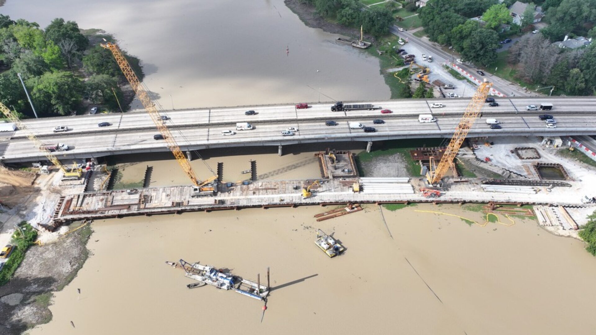 A birds-eye view of temporary trestle bridge and heavy equipment constructing new westbound lanes on I-10 across City Park Lake in Baton Rouge.